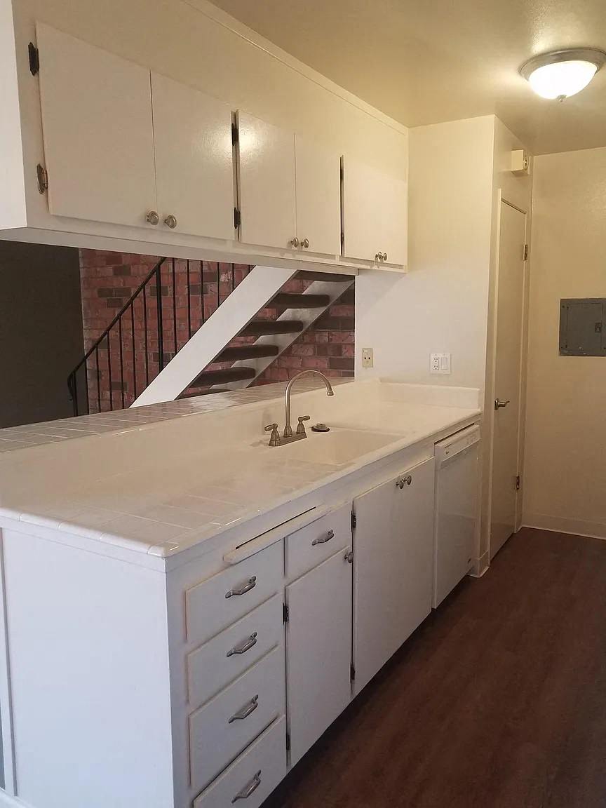 A kitchen with white cabinets and a brick wall.